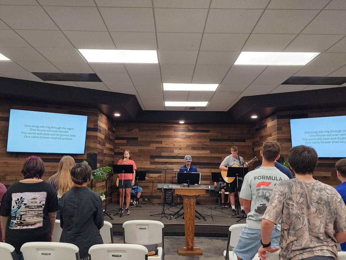 Students gathered for Rooted Youth in a room with a worship band and screens