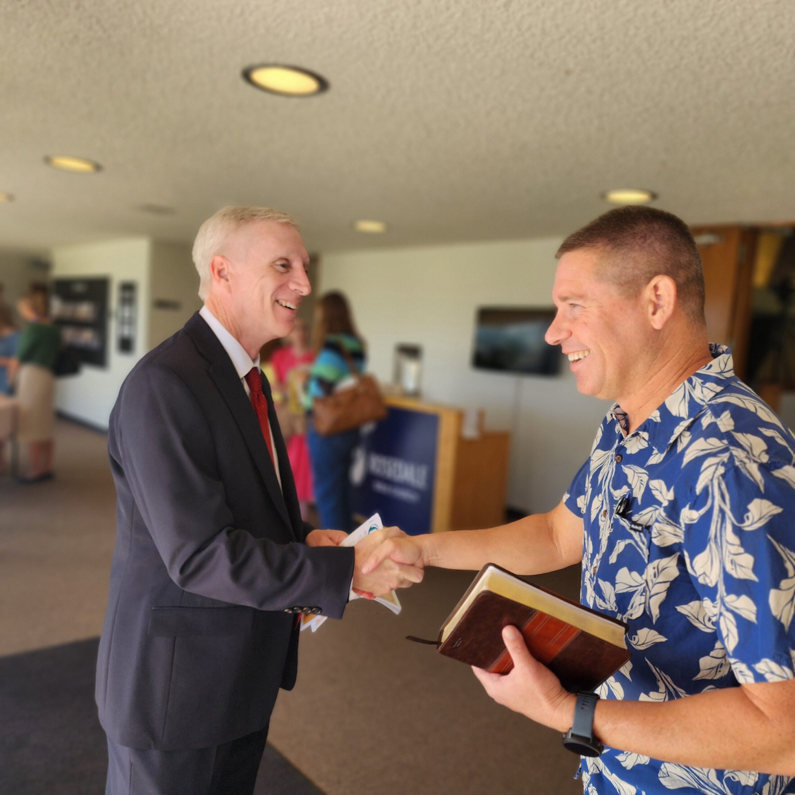 Two men smile and shake hands inside Rosedale Bible Church on a Sunday morning